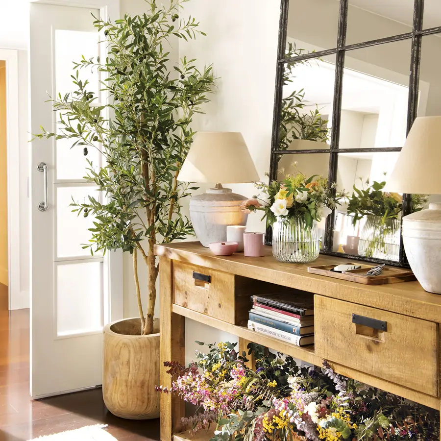 recibidor con mueble de madera rústica con espejo, olivo y flores secas, lámparas de mesa y jarrón de cristal